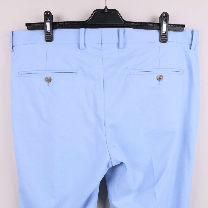 Närbild på bakfickor med knappar på ljusblå byxa