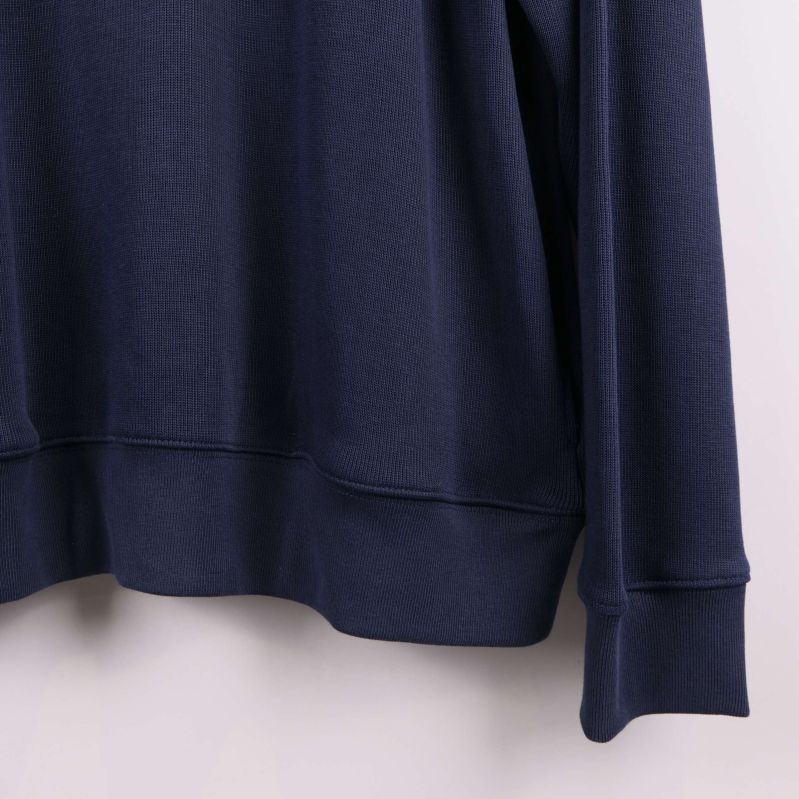 Närbild på höger nederkant och muddar av blå tröja