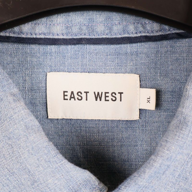 Närbild på etikett med texten EAST WEST XL