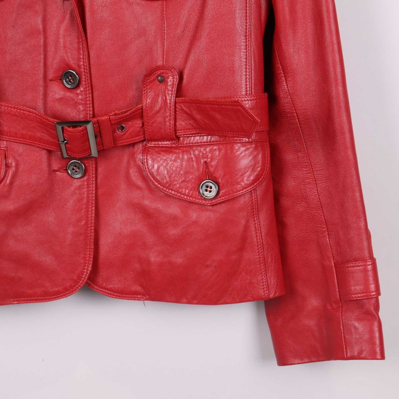 Närbild på knapp och bältdetalj på jackans nederdel