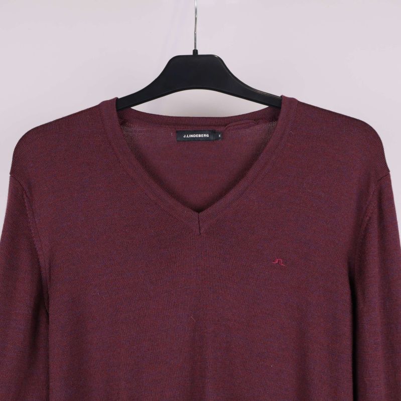 Närbild på v-ringning och logga framtill på tröjan