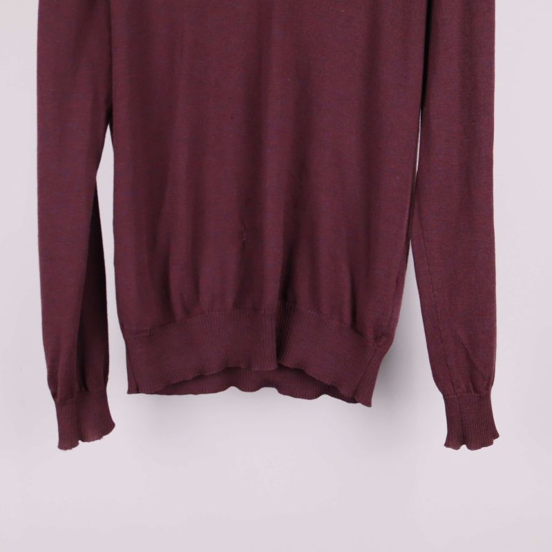 Nederkant och ärmslut på vinröd tröja i närbild