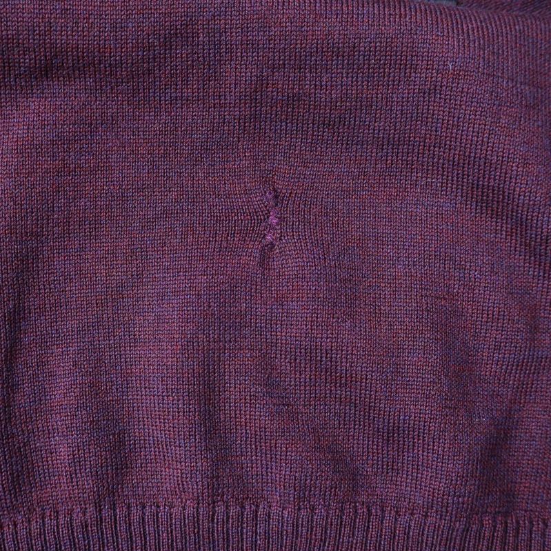 Närbild på mindre lagning eller defekt på tröjan