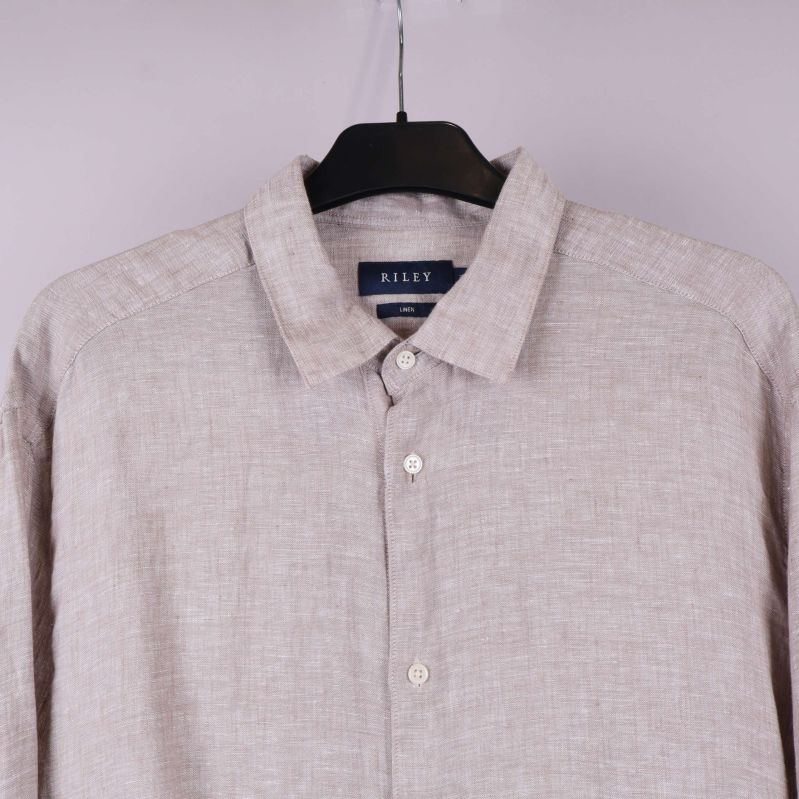 Närbild på krage och överdel av ljusbeige linneskjorta