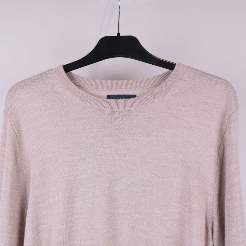 Närbild av halsringning och axel på beige tröja