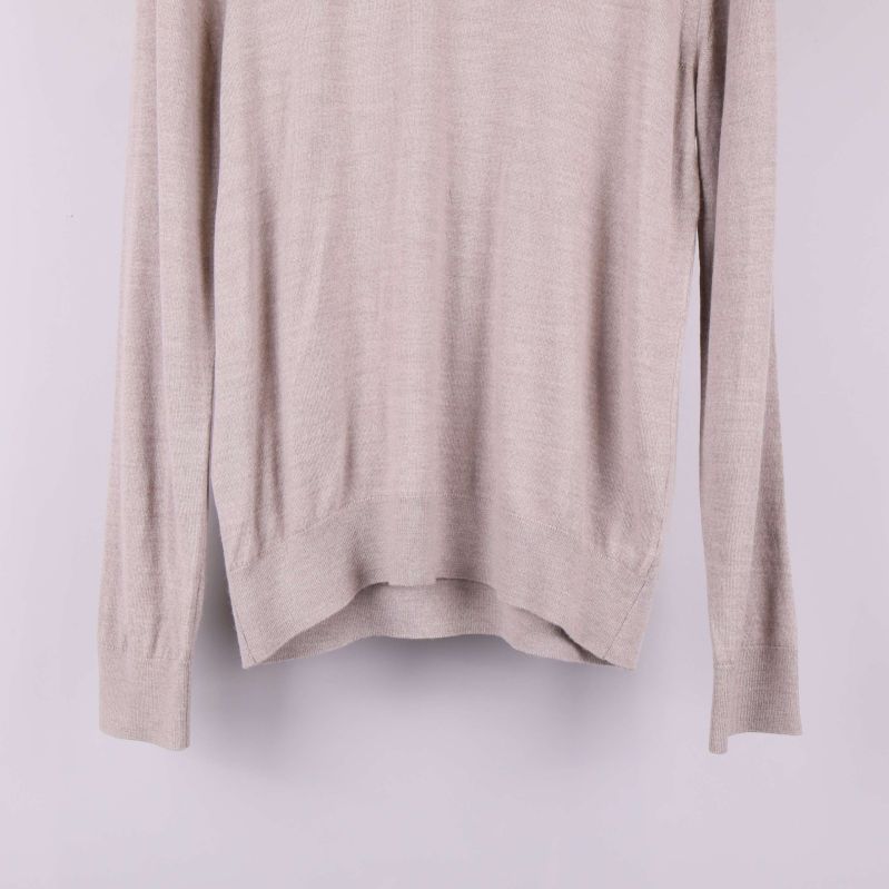 Närbild av nederkant och ärmar på beige tröja