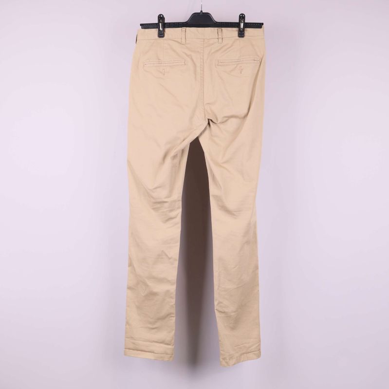 Baksida av beiga byxor med fickor på galge