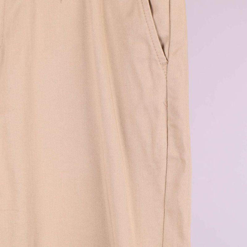 Närbild på sidosöm och ficka på beiga byxor