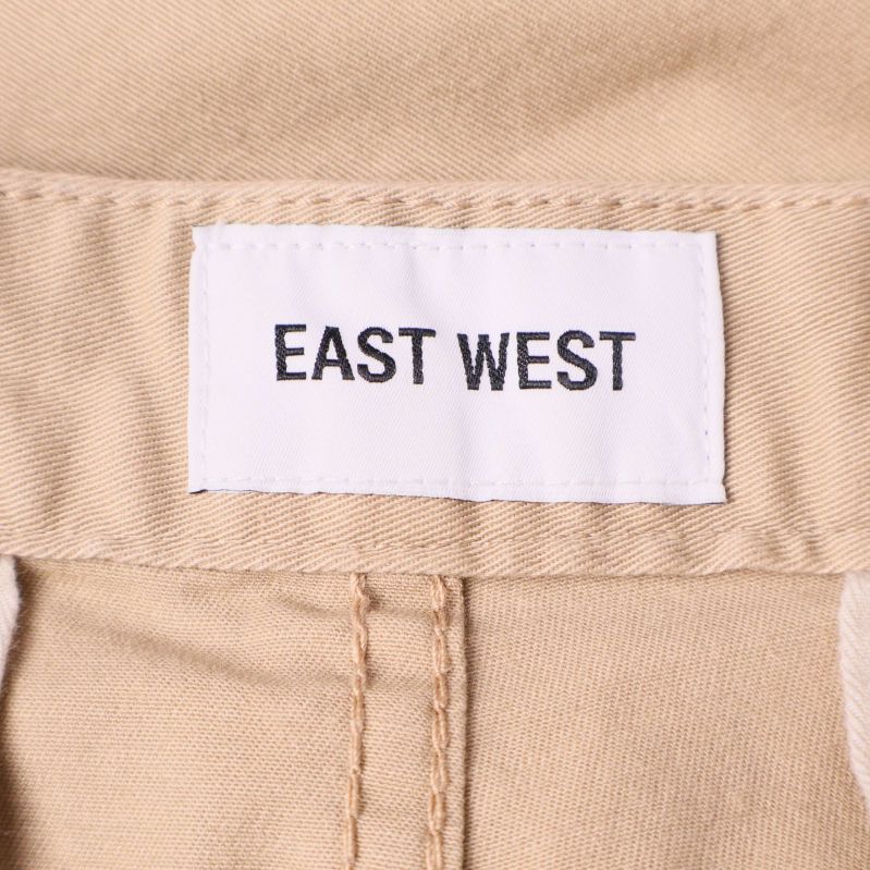 Närbild på etikett med varumärket East West i midjan