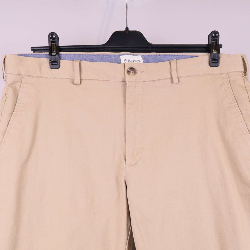 Detaljbild av midja och fickor på beigea byxor