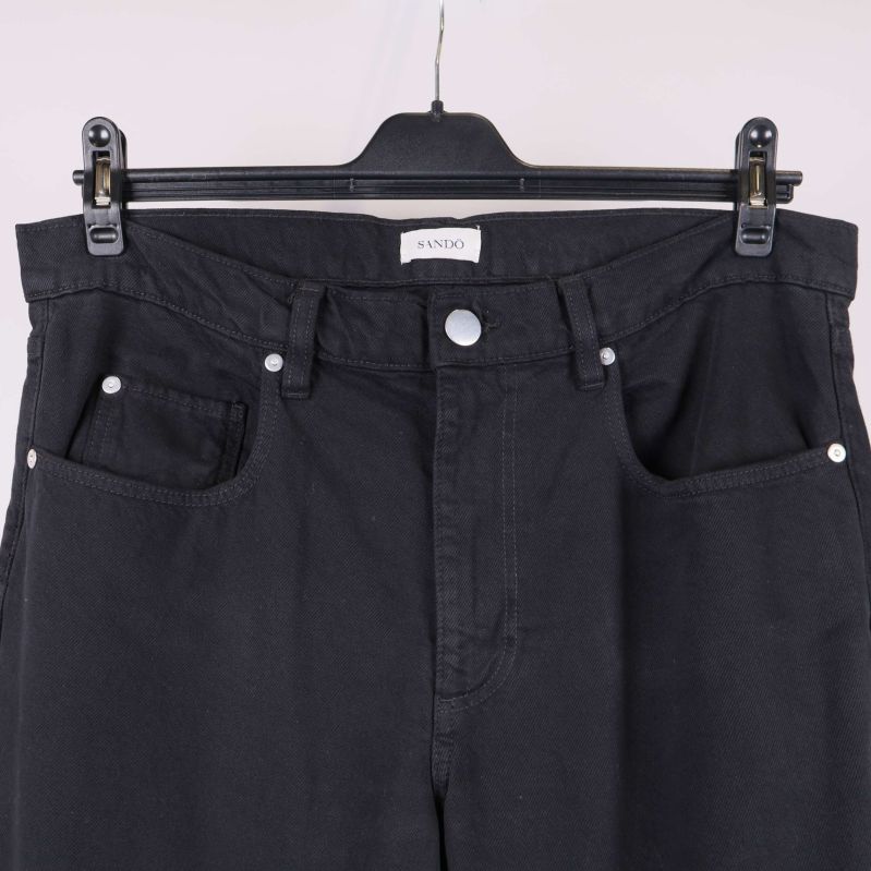 Närbild på framfickor och knapp på svarta byxor