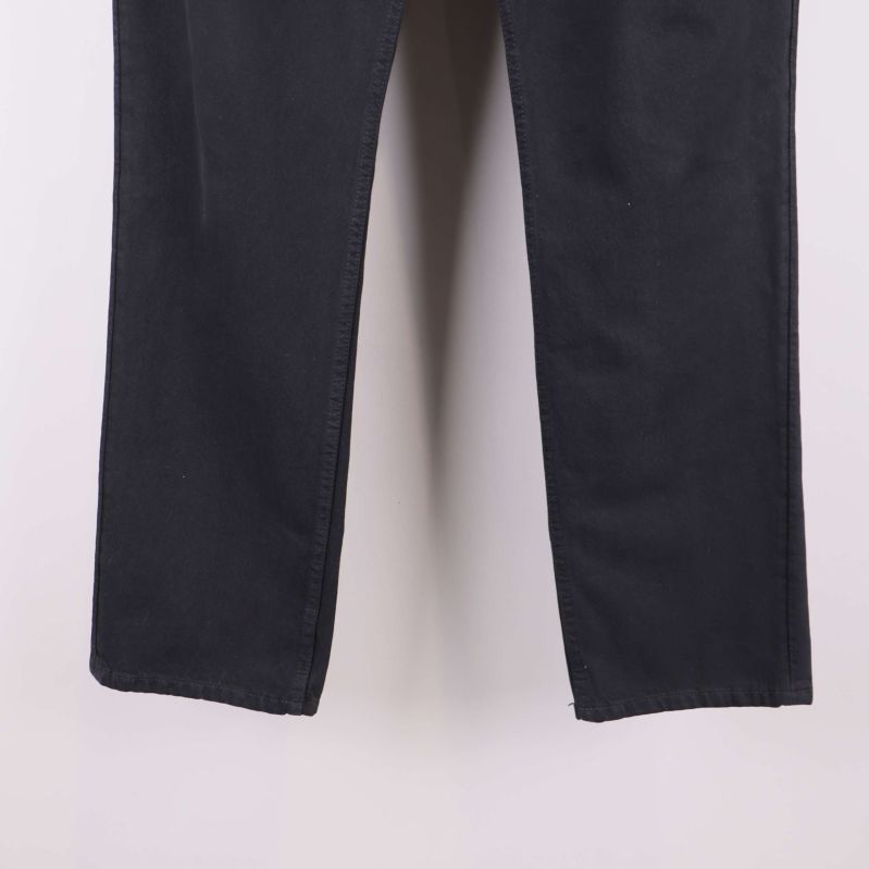 Närbild på benslutet av svarta raka byxor