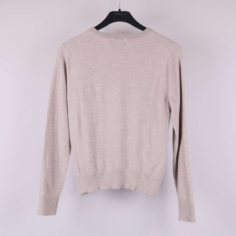 Beige stickad tröja med långa ärmar bakifrån på galge