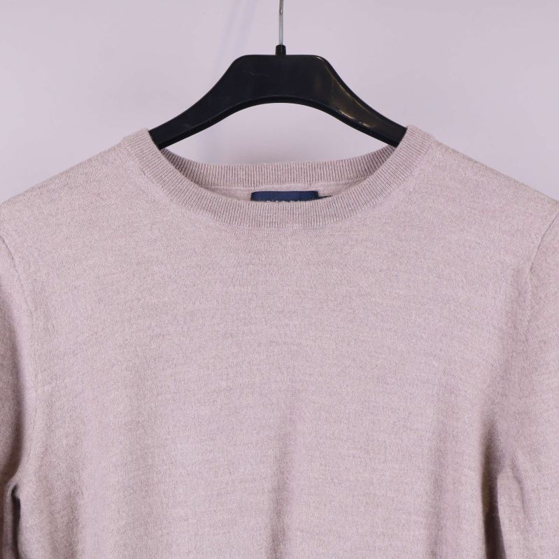 Närbild på halsringning och övre del av beige stickad tröja