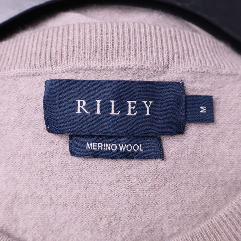 Närbild på RILEY-märkeslapp och materialetikett merinoull