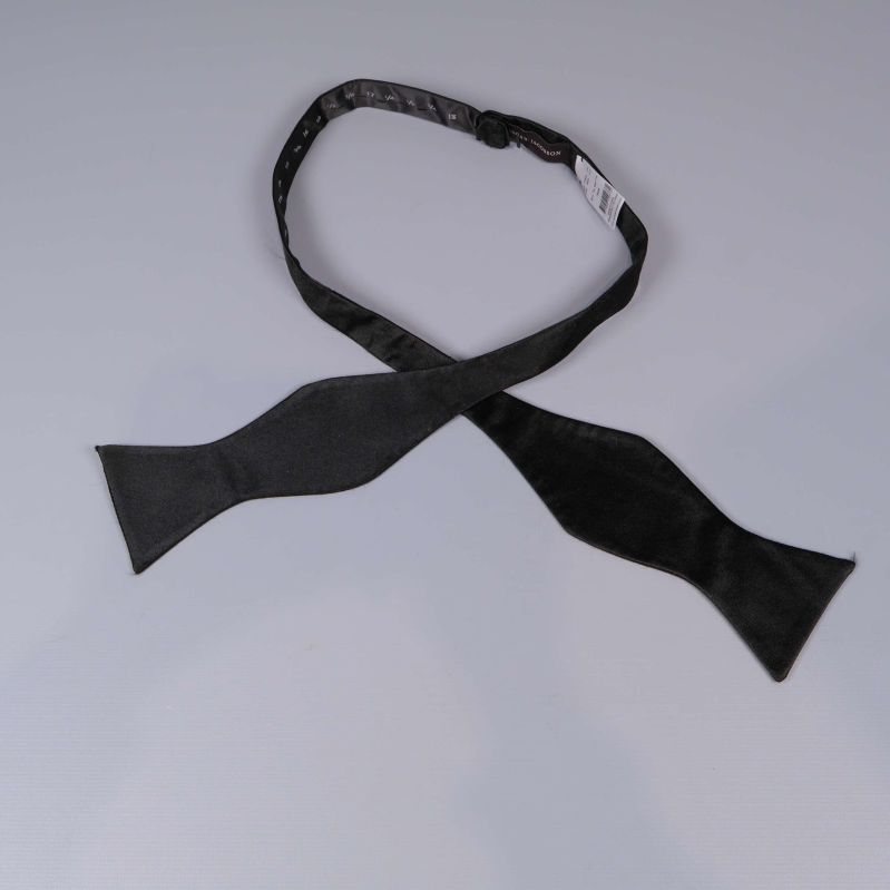 Svart självknutande fluga utlagd på ljus yta