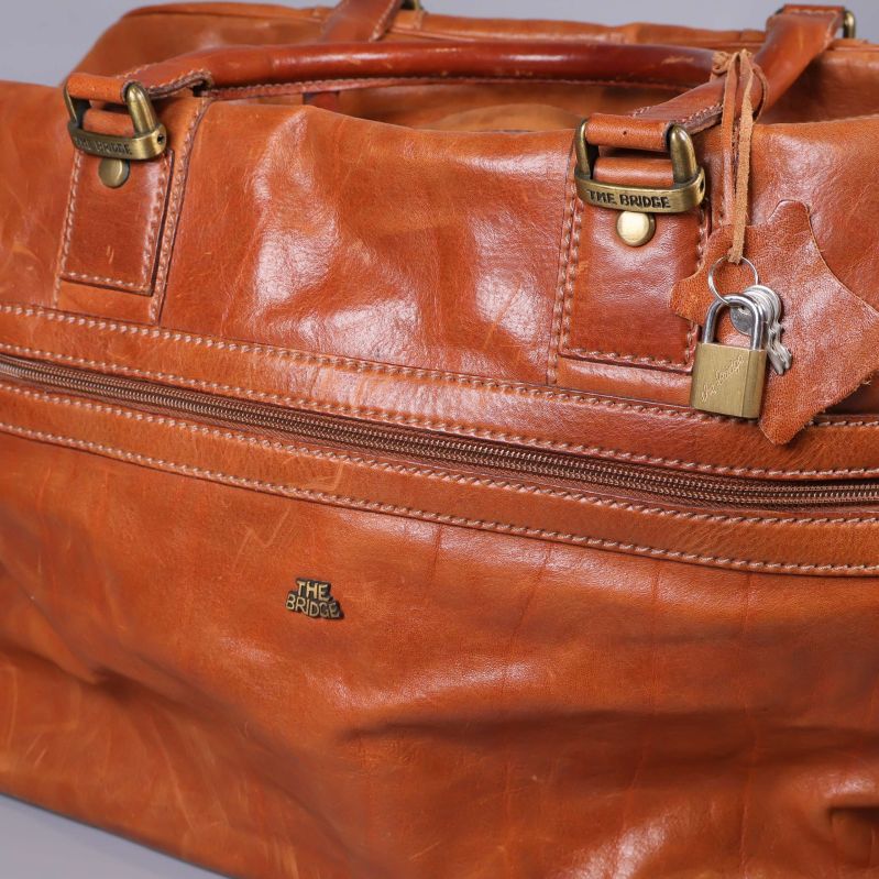 Närbild på läderväska med dragkedja och lås, detaljer i metall