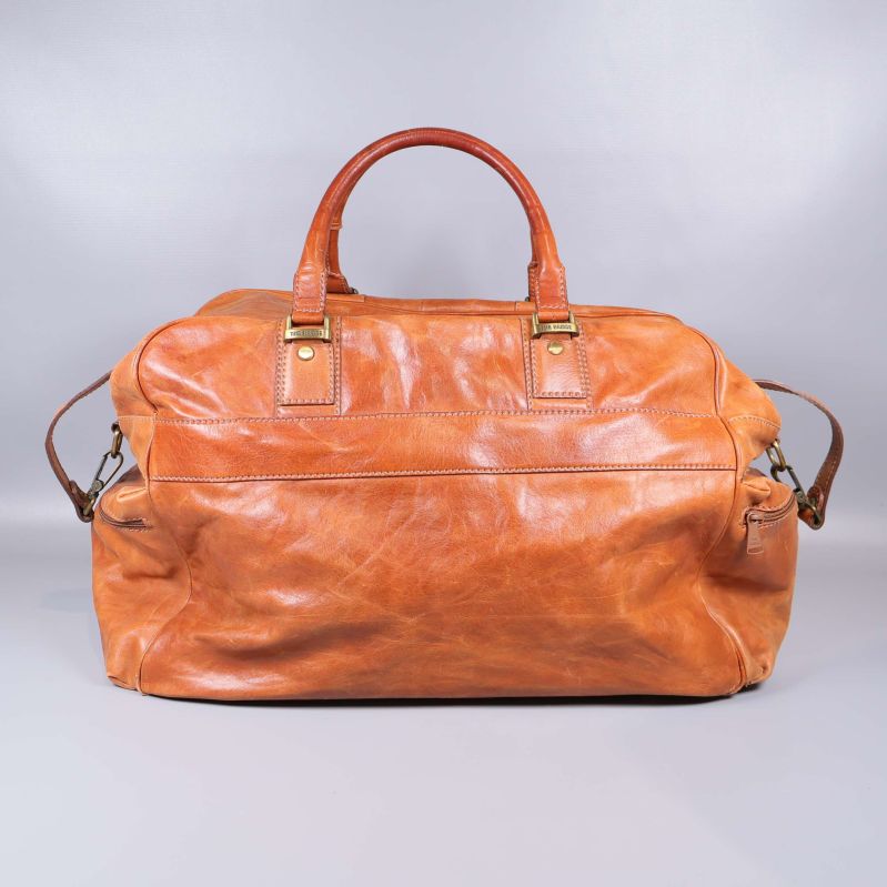 Baksida av weekendväska i läder med två handtag och metallbeslag