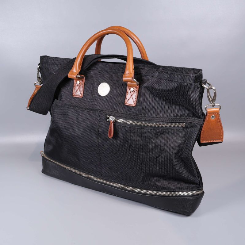 Svart weekendbag med bruna handtag och axelrem