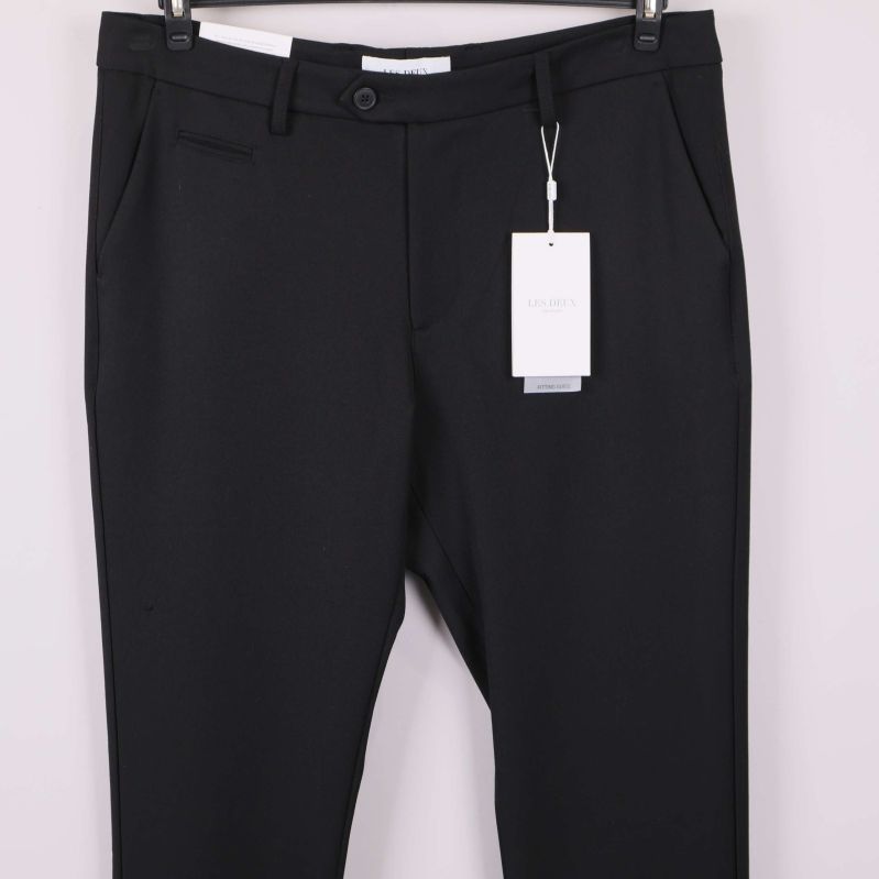 Framdel av svarta kostymbyxor med fickor och etikett