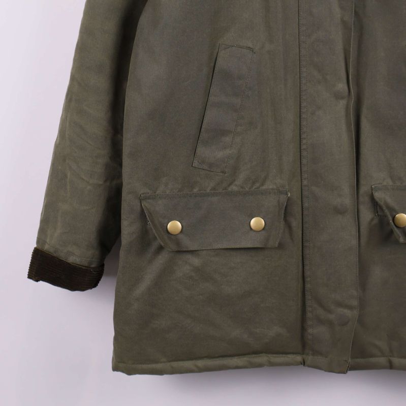 Närbild på jackficka med tryckknappar och manschett