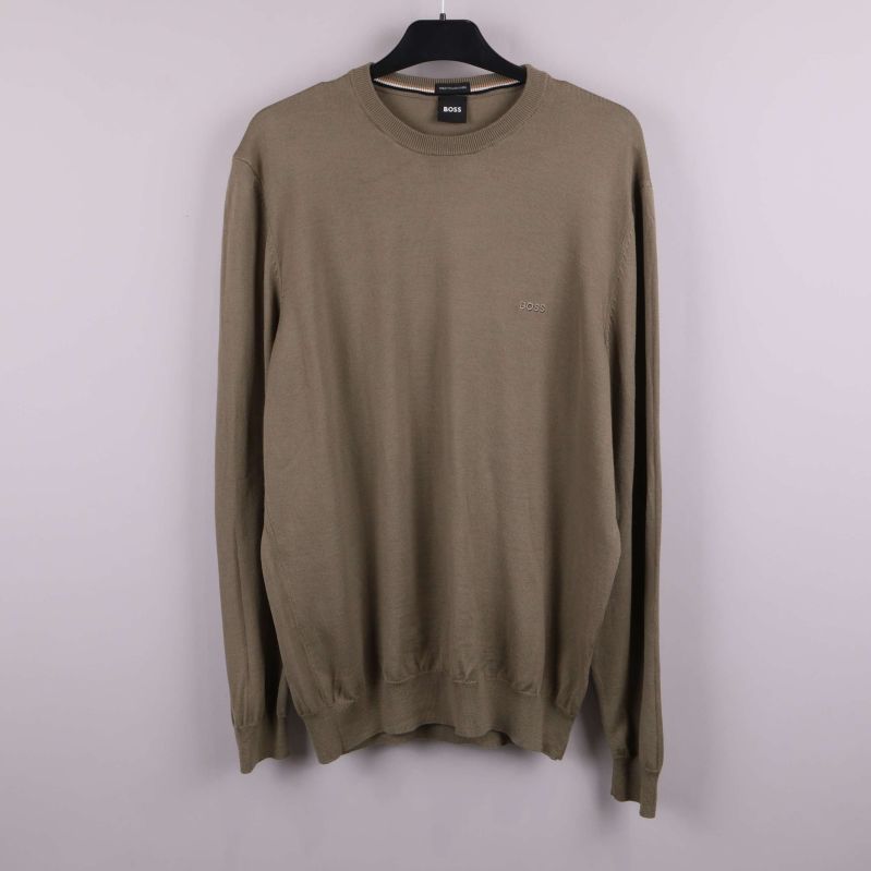 Beige stickad tröja på galge mot ljus bakgrund