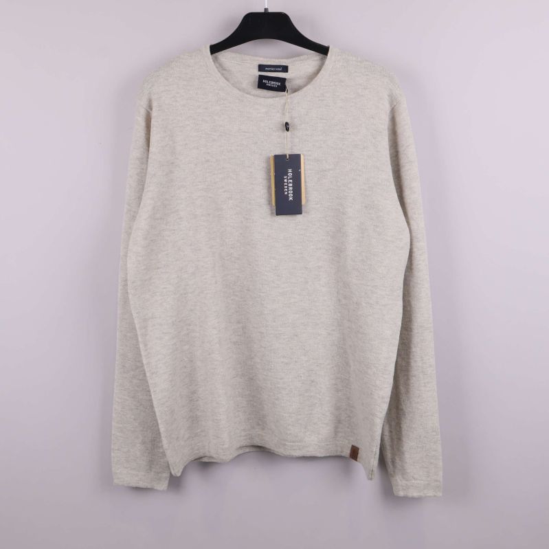 Beige långärmad tröja på galge mot ljus bakgrund