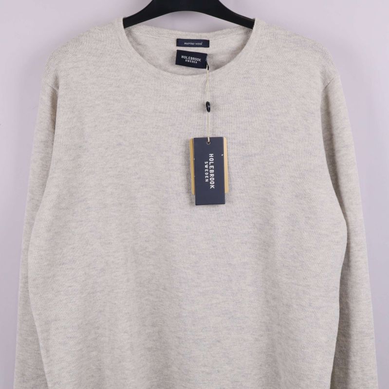 Närbild på beige tröjas framsida och etikett