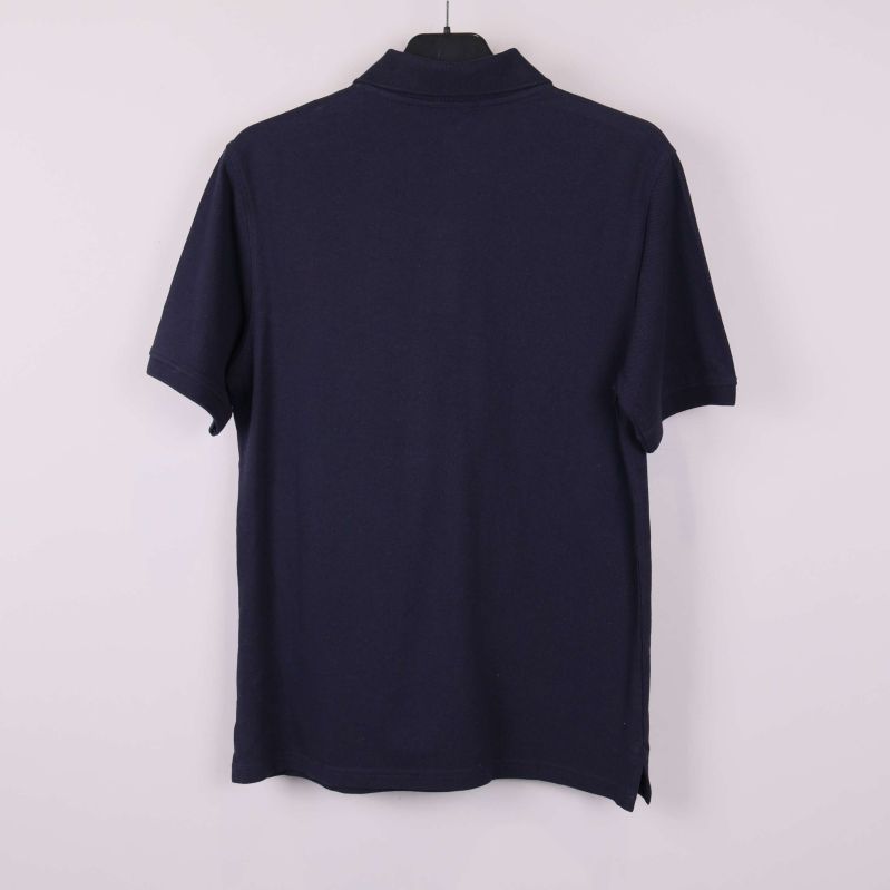 Mörkblå pikétröja bakifrån mot ljus bakgrund