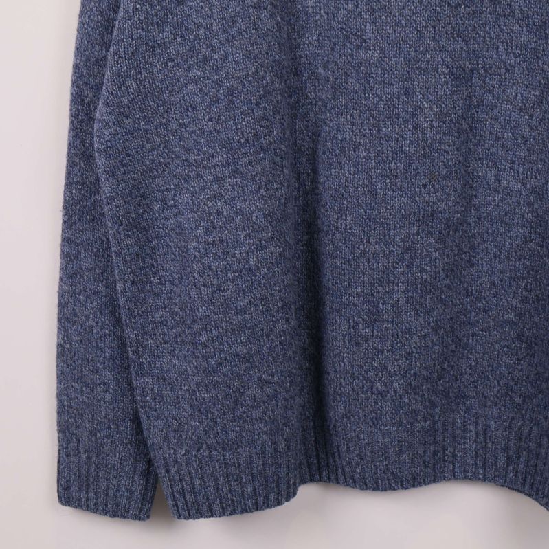 Nedre del av blå stickad tröja med ribbade muddar