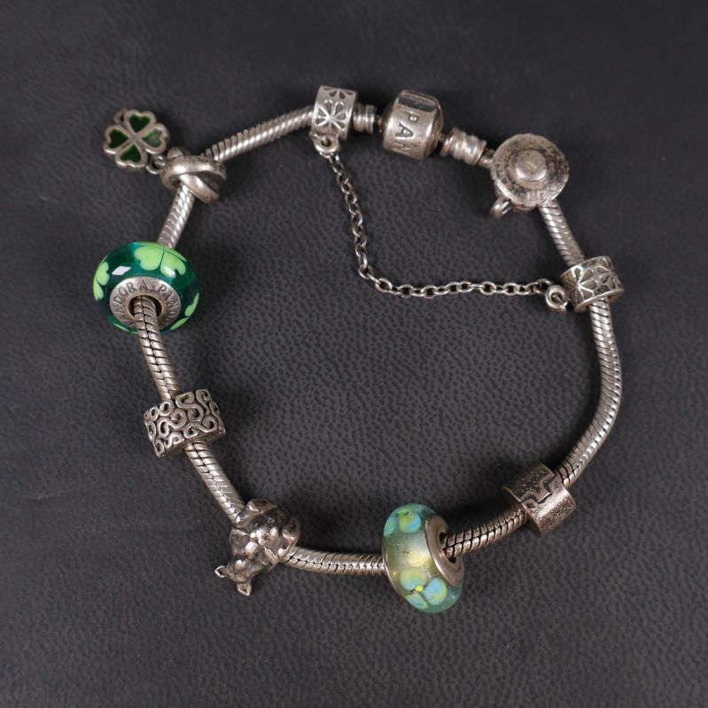 Närbild på charmarmbandets berlocker och glaspärlor
