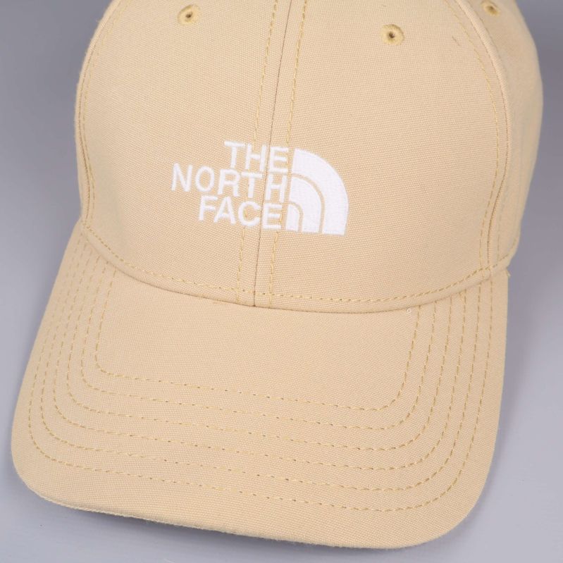 Närbild på The North Face-logotyp på beige keps