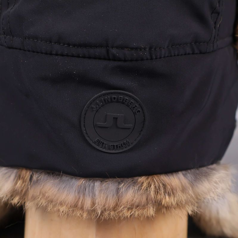 Närbild av JL-märke på svart mössa med fuskpäls