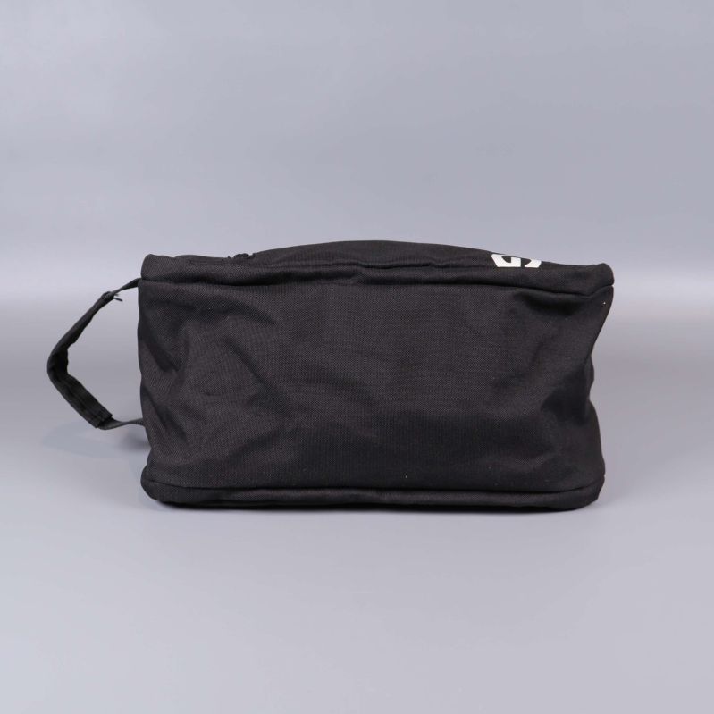 Necessär i svart tyg sedd underifrån med handtag åt vänster