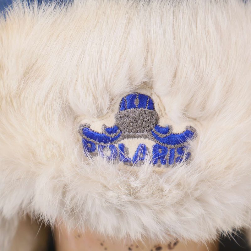 Broderad blå logga på fuskpälsen framtill på mössan