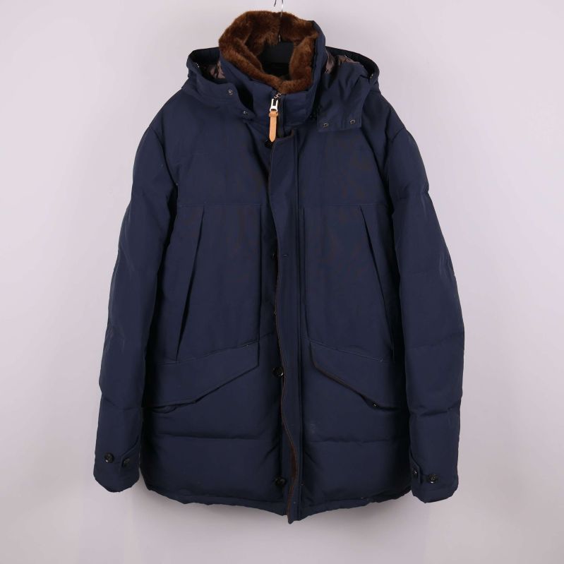 Mörk vadderad jacka med huva framifrån mot vit bakgrund