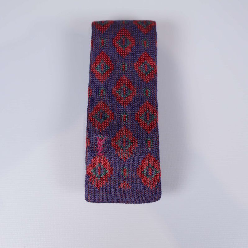 Stickad slips med grafiskt rött mönster på lila botten