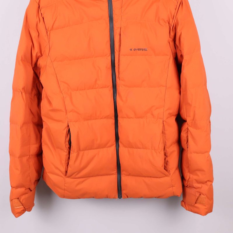 Närbild på nedre delen av orange jacka och fickor