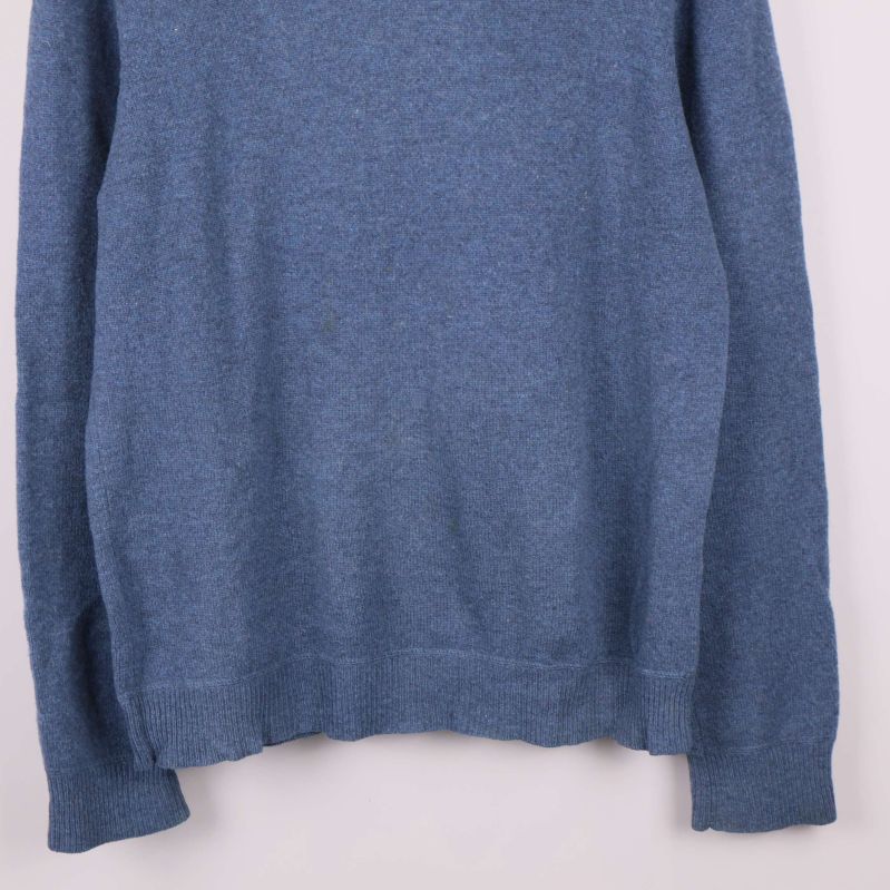 Nedre del av blå stickad tröja visar fåll och mudd