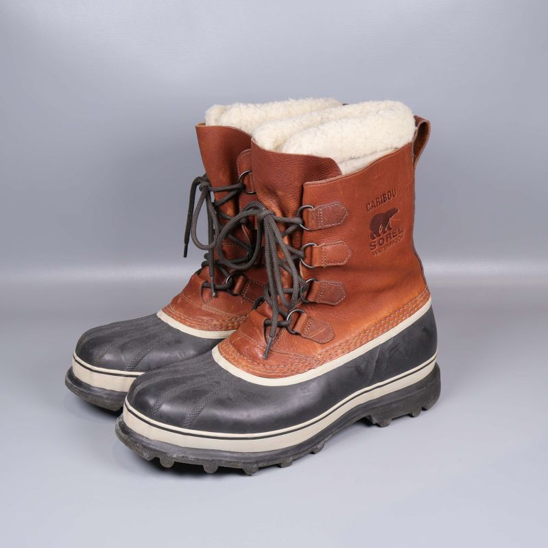 Vinterkängor med brun ovandel, svart sula och vitt foder i sidovy