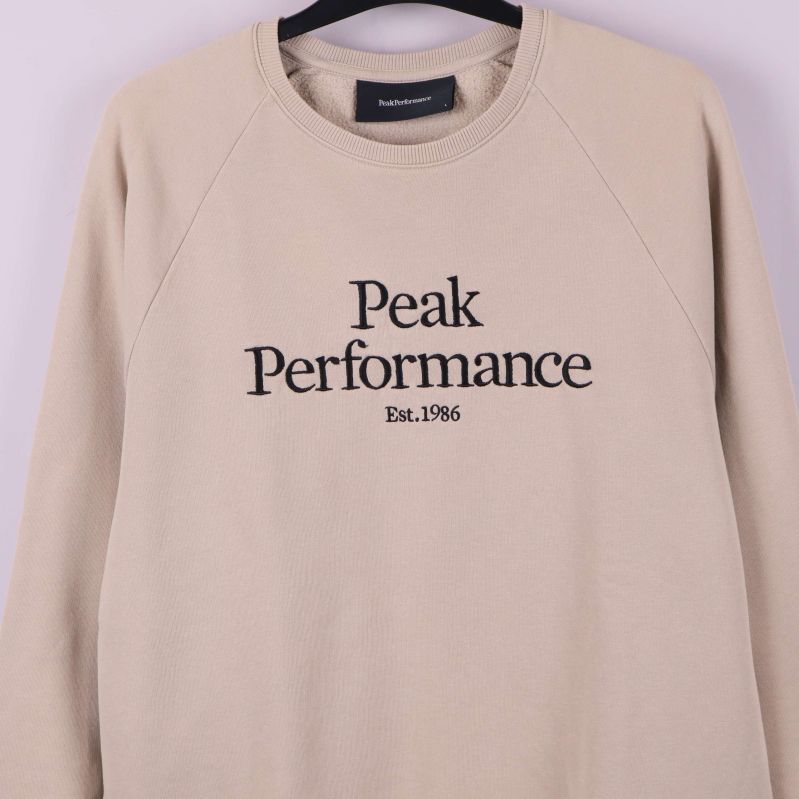 Närbild av logotypen Peak Performance broderad på bröstet