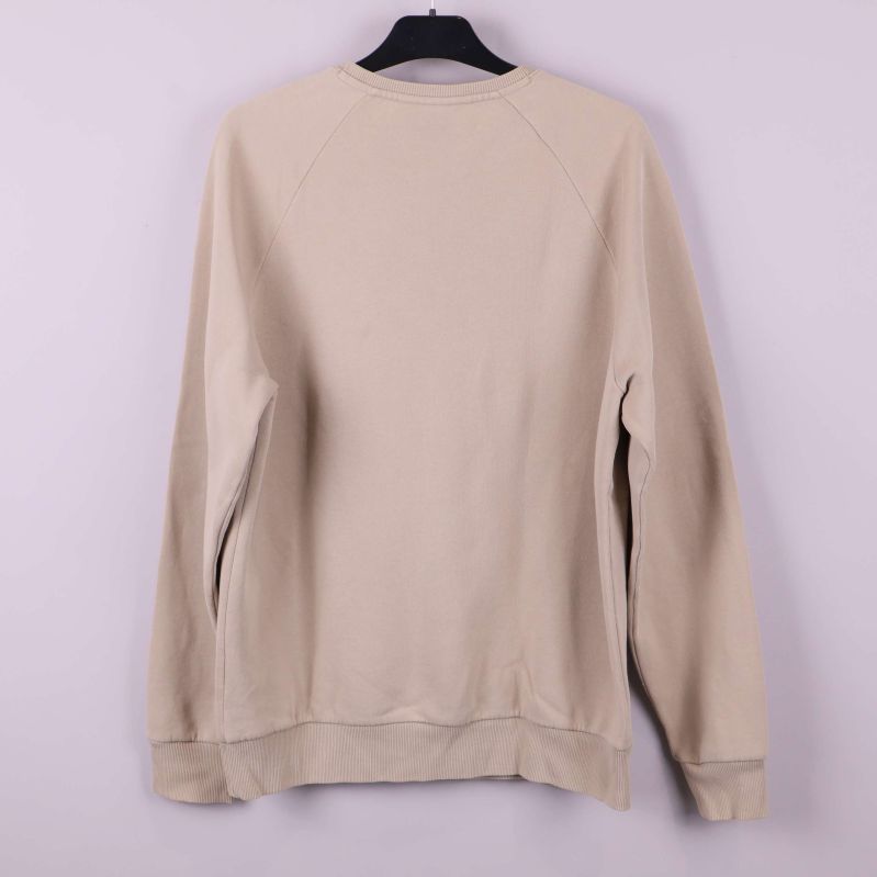 Baksida av beige Peak Performance sweatshirt på galge