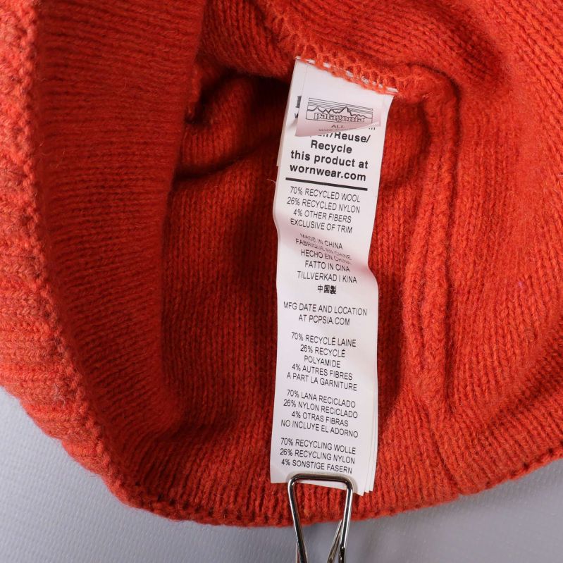 Materialetikett invändigt i orange stickad mössa