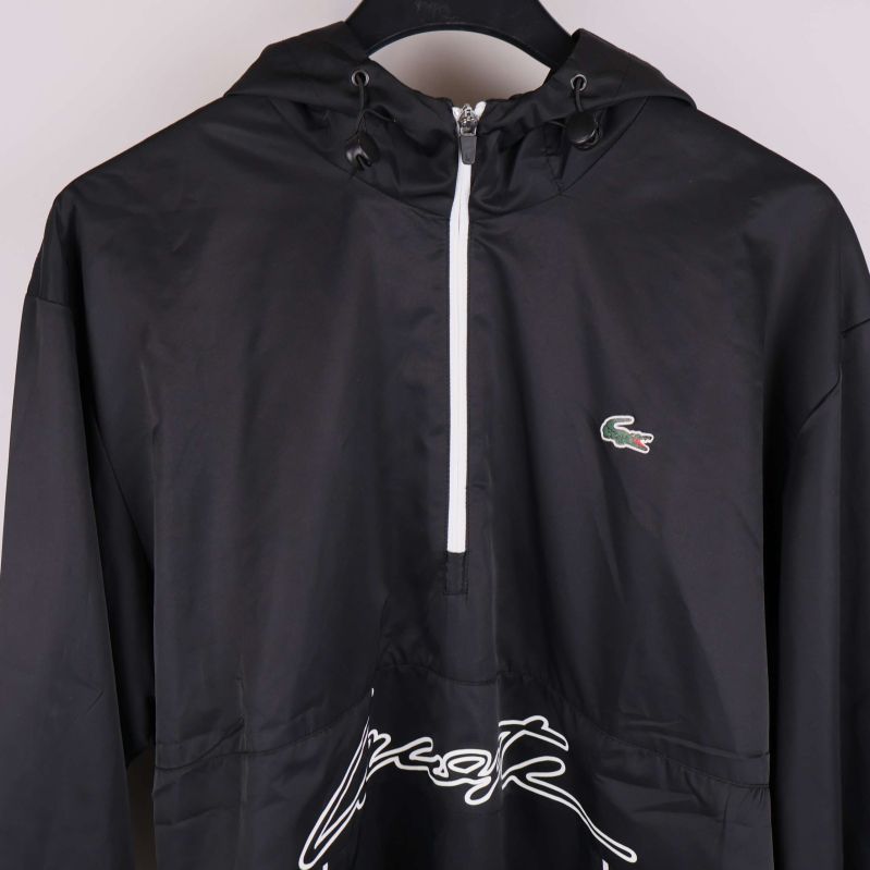 Närbild på ovandelen med dragkedja och Lacoste-märke