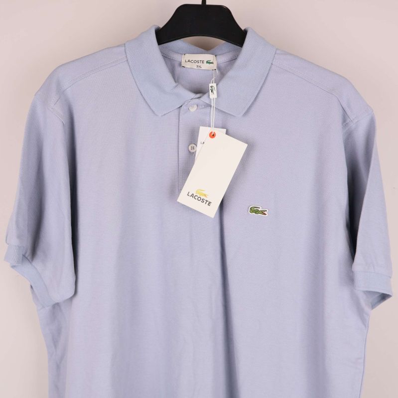 Ljusblå pikétröja med hängande tagg och logotyp