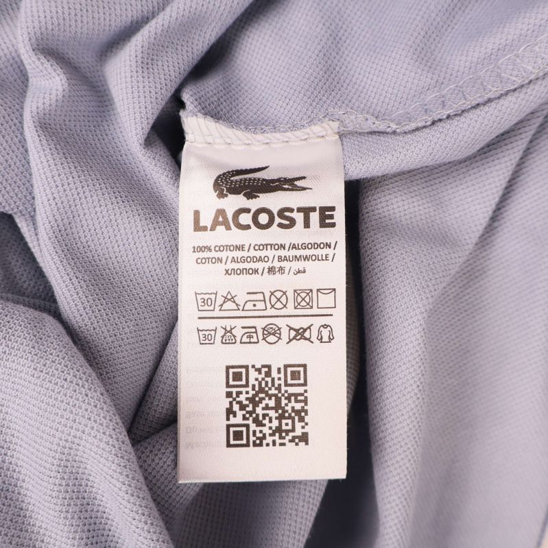 Tvättetikett Lacoste visar 100% bomull och tvättråd