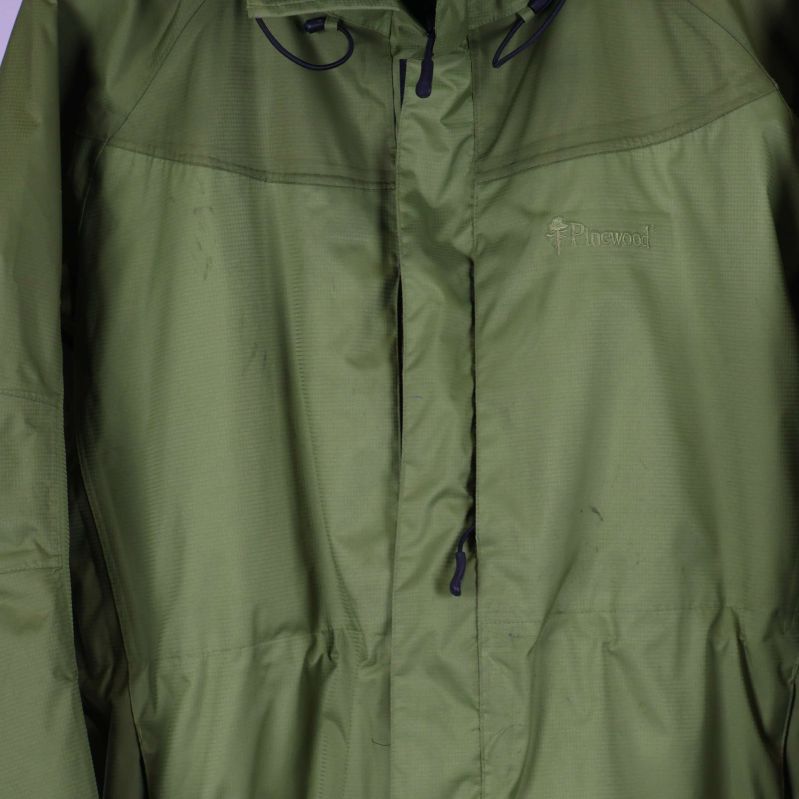 Dragkedja och knappslå framtill på grön jacka