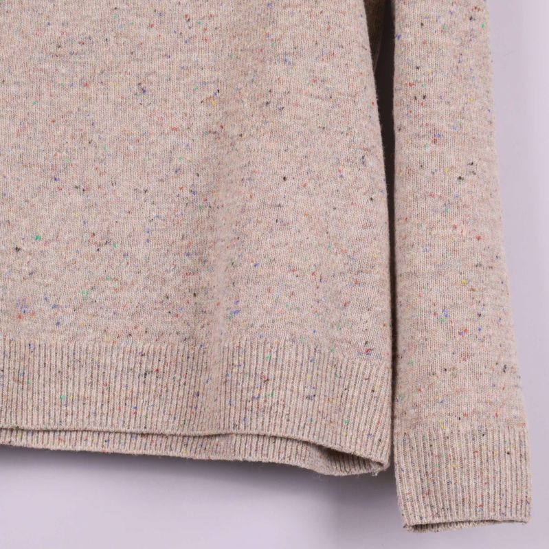 Ärmslut och sidoparti på beige tröja med färginslag