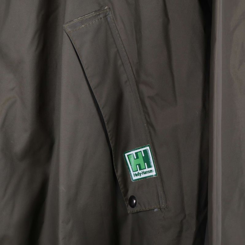 Närbild på logomärke vid fickan på olivgrön jacka