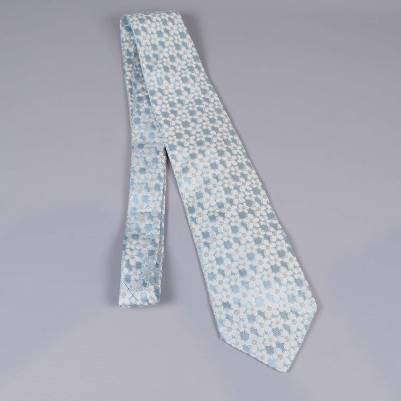 Ljusblå slips med vitt blommönster i vinklad vy